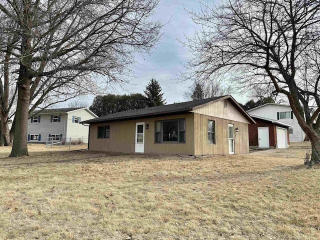 rear view of property featuring a garage and a yard