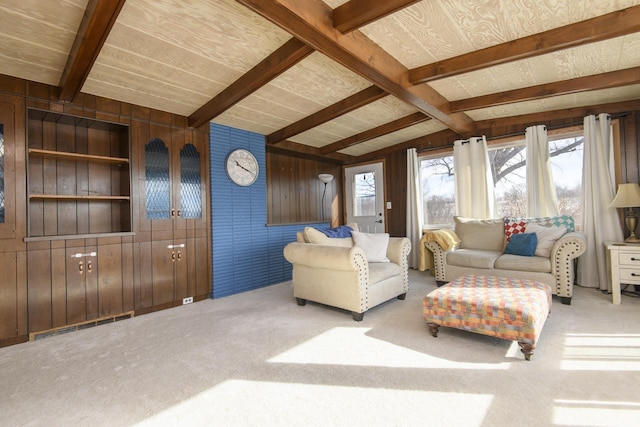 carpeted living area with wooden walls, visible vents, and lofted ceiling with beams