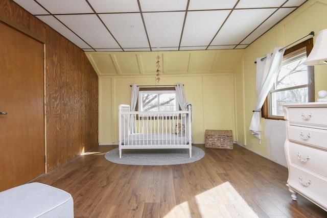 unfurnished bedroom featuring a paneled ceiling, multiple windows, and wood finished floors