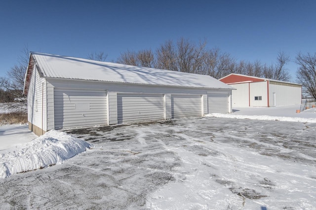 snow covered garage featuring a detached garage