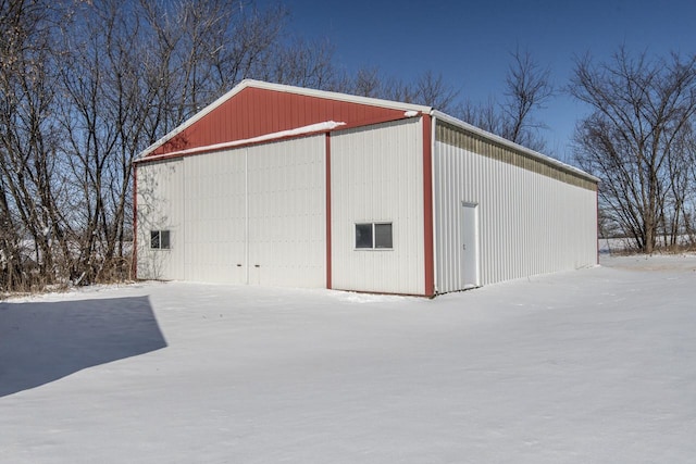 snow covered structure with a pole building and an outbuilding