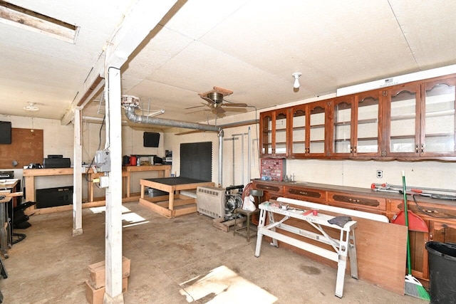 miscellaneous room with concrete flooring, a workshop area, and a ceiling fan