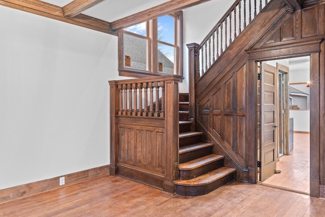 staircase with wood-type flooring and beam ceiling