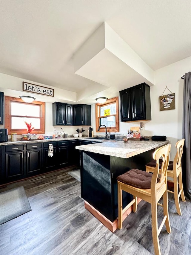 kitchen with sink, a breakfast bar area, dark wood-type flooring, and kitchen peninsula