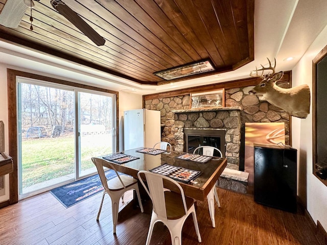 dining area with a raised ceiling, hardwood / wood-style flooring, a fireplace, and wood ceiling