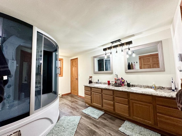 bathroom featuring wood-type flooring, vanity, a textured ceiling, and a shower with shower door