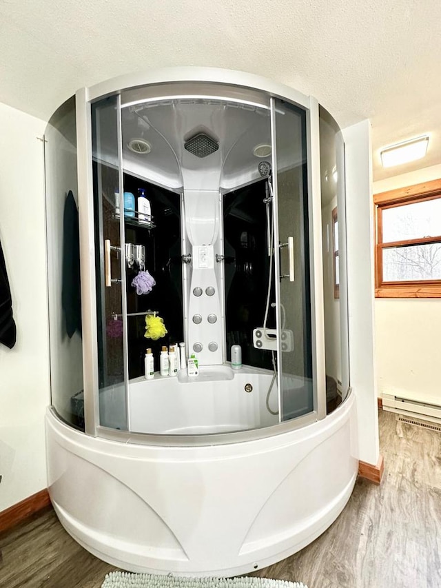 interior space featuring hardwood / wood-style flooring, a baseboard radiator, shower / bath combination with glass door, and a textured ceiling