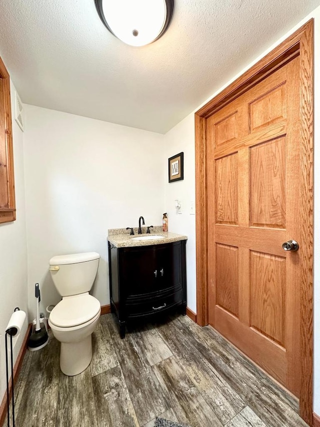 bathroom with vanity, wood-type flooring, a textured ceiling, and toilet