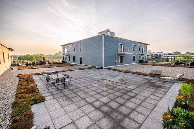 back house at dusk featuring a patio