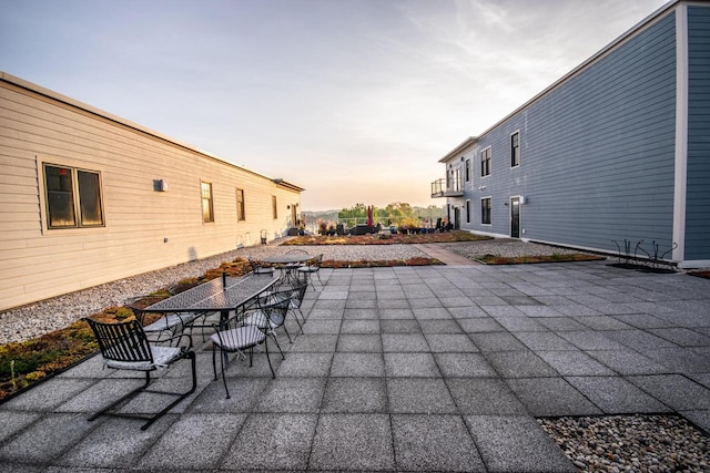 patio terrace at dusk featuring a balcony