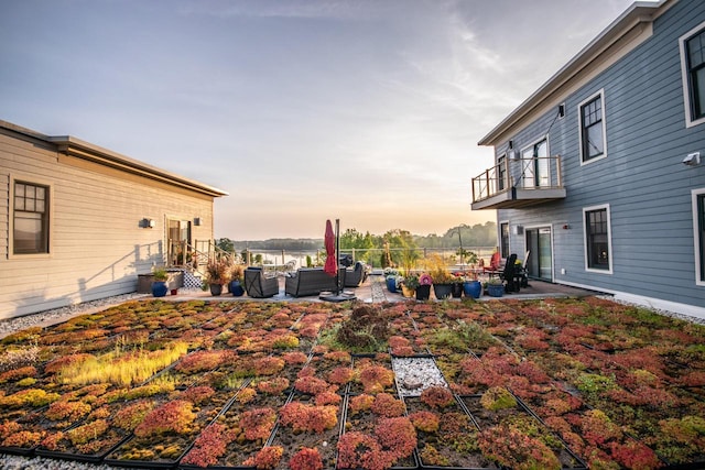 yard at dusk featuring a patio area, outdoor lounge area, and a balcony