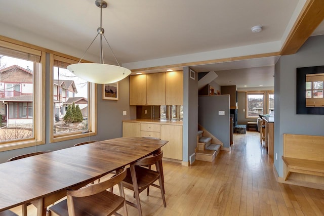 dining room with stairs, light wood finished floors, and baseboards