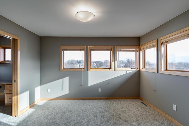 carpeted spare room featuring plenty of natural light and baseboards