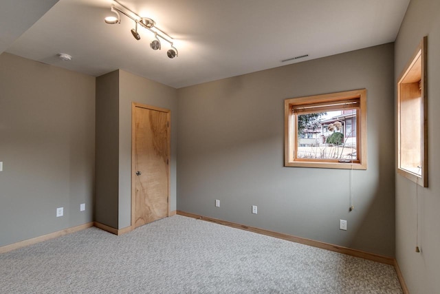 unfurnished bedroom featuring carpet, baseboards, visible vents, and track lighting