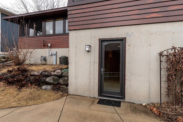 entrance to property featuring central air condition unit and stucco siding