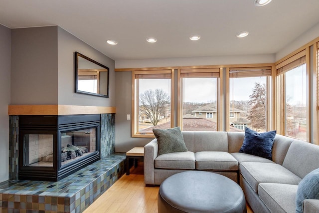 living area featuring recessed lighting, wood finished floors, a wealth of natural light, and a multi sided fireplace