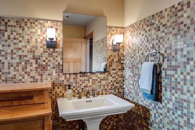 bathroom with backsplash, a sink, and tile walls