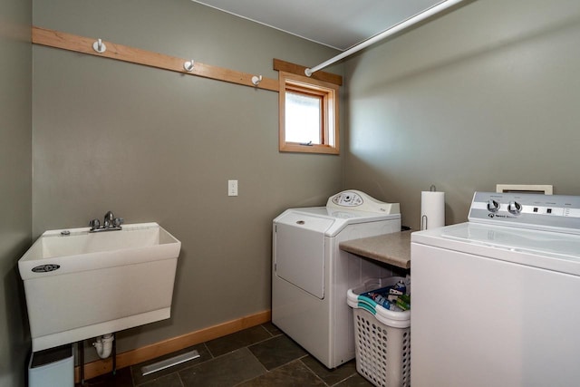 washroom with washing machine and dryer, laundry area, dark tile patterned floors, a sink, and baseboards