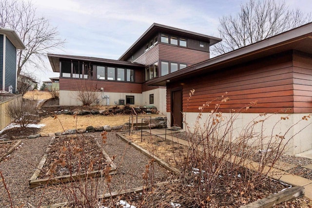 view of property exterior featuring a sunroom and a vegetable garden