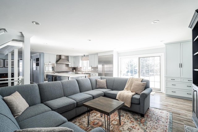 living room featuring light hardwood / wood-style flooring, sink, and crown molding