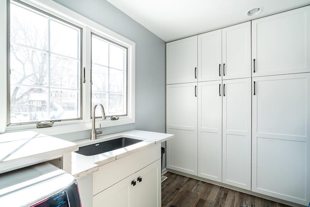 kitchen featuring sink, white cabinetry, dark hardwood / wood-style floors, washer / clothes dryer, and light stone countertops