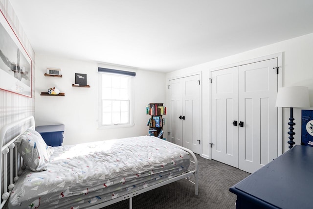 bedroom with dark colored carpet and two closets