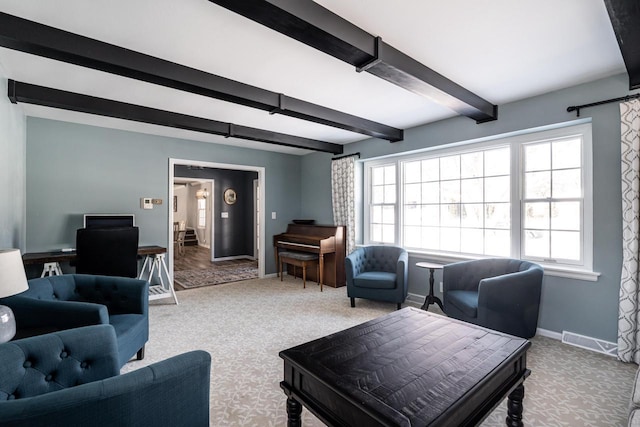 carpeted living room with beamed ceiling