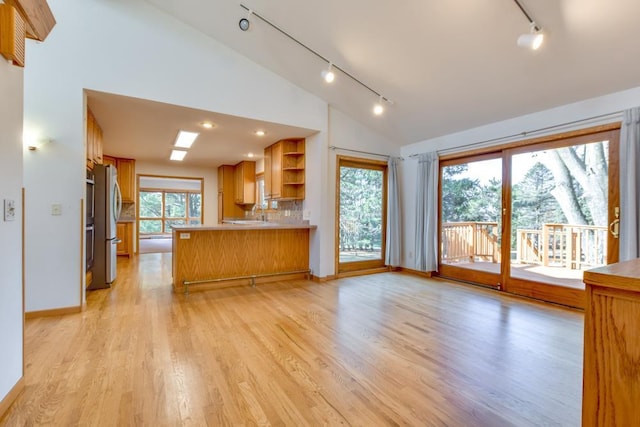 kitchen featuring open shelves, freestanding refrigerator, a peninsula, light wood finished floors, and lofted ceiling