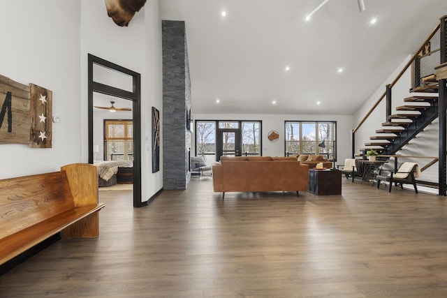 living room featuring ceiling fan, a towering ceiling, and dark hardwood / wood-style flooring