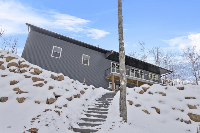 snow covered rear of property featuring a balcony