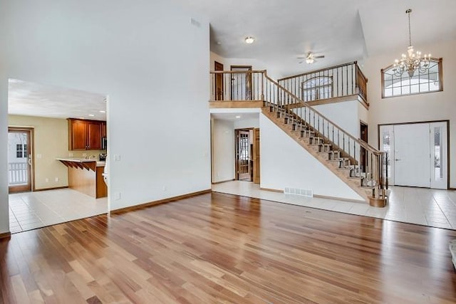 unfurnished living room with a high ceiling, plenty of natural light, and light hardwood / wood-style flooring