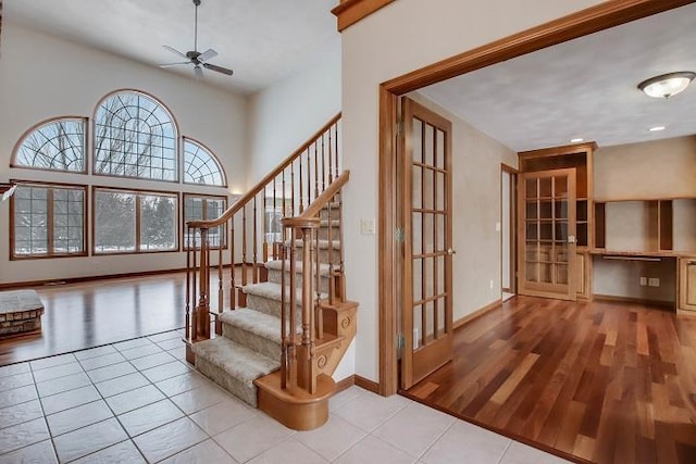 stairway featuring a high ceiling, tile patterned floors, and ceiling fan