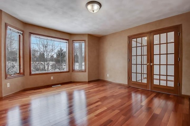 unfurnished room featuring french doors and light wood-type flooring