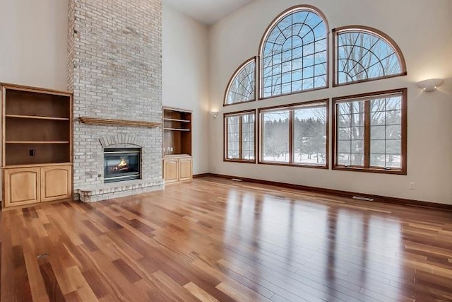 unfurnished living room with a high ceiling, a fireplace, and light hardwood / wood-style flooring