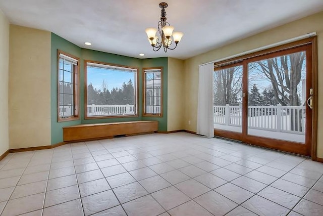 tiled spare room with a notable chandelier