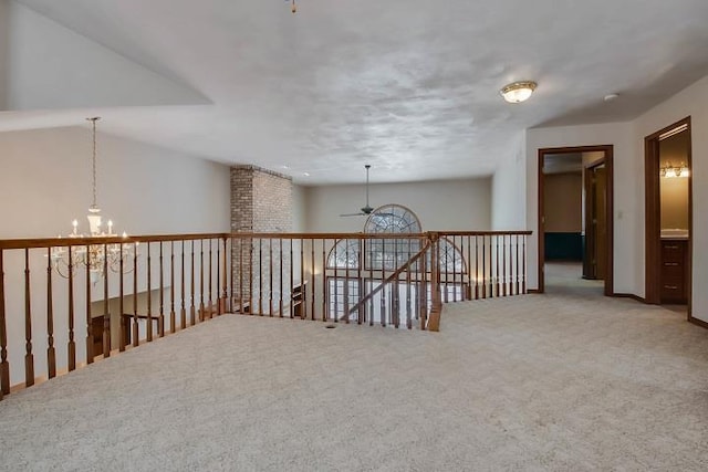 carpeted empty room with ceiling fan with notable chandelier