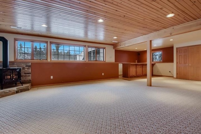 interior space with carpet flooring, wooden ceiling, and a wood stove