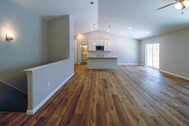 unfurnished living room featuring vaulted ceiling, dark hardwood / wood-style floors, sink, and ceiling fan