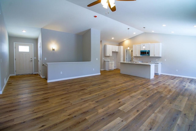 unfurnished living room with lofted ceiling, sink, dark hardwood / wood-style floors, and ceiling fan