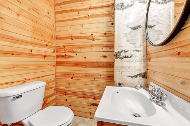 bathroom featuring toilet, vanity, and wood walls