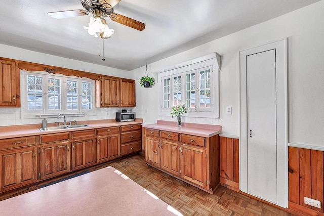 kitchen with tasteful backsplash, ceiling fan, sink, and light parquet floors