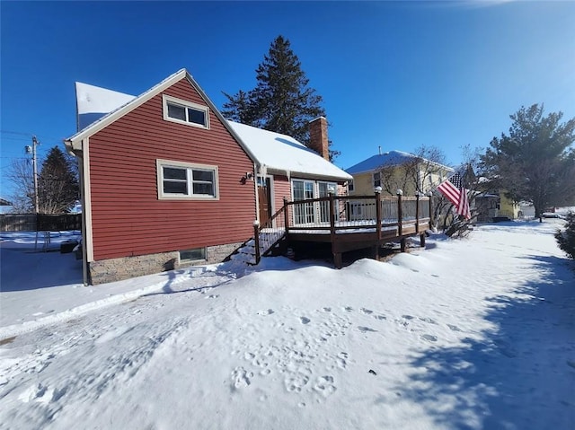 snow covered back of property featuring a wooden deck