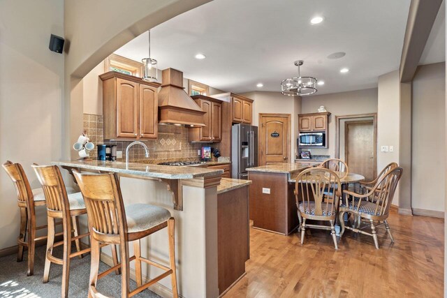 6507 Willow Ct, Waterford, WI 53185 - kitchen with custom exhaust hood, appliances with stainless steel finishes, pendant lighting, and kitchen peninsula