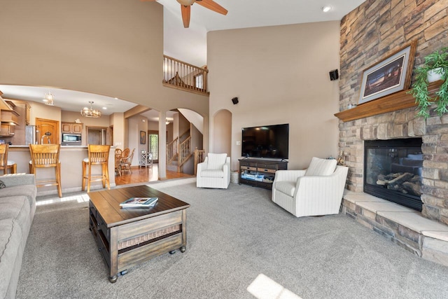 6507 Willow Ct, Waterford, WI 53185 - living room with ceiling fan with notable chandelier, a fireplace, a towering ceiling, and carpet flooring