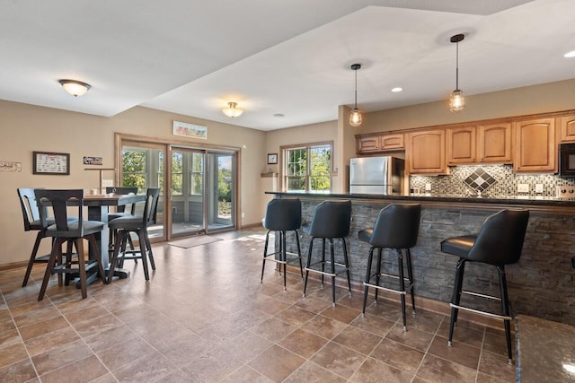 6507 Willow Ct, Waterford, WI 53185 - kitchen featuring tasteful backsplash, a breakfast bar, pendant lighting, and stainless steel refrigerator