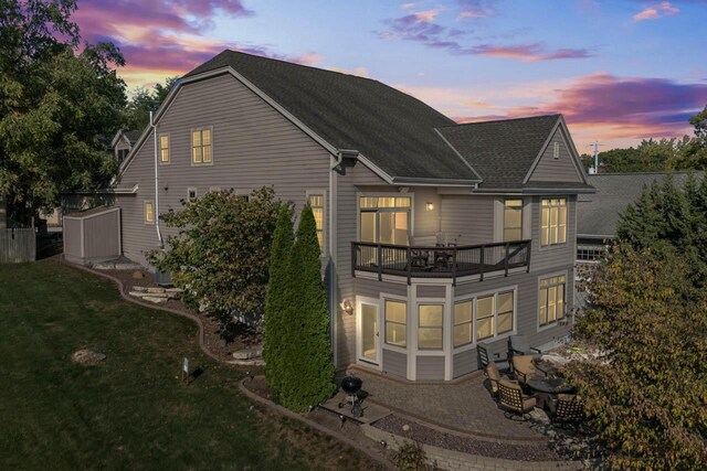 6507 Willow Ct, Waterford, WI 53185 - back house at dusk with a balcony and a lawn