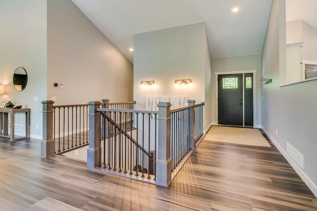 entrance foyer with high vaulted ceiling, wood finished floors, visible vents, and baseboards