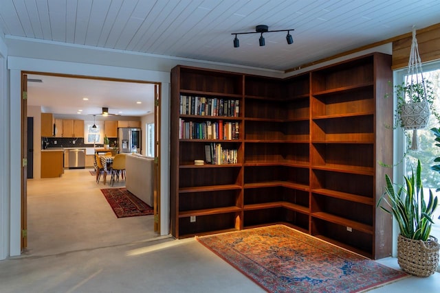 living area featuring wood ceiling and concrete flooring