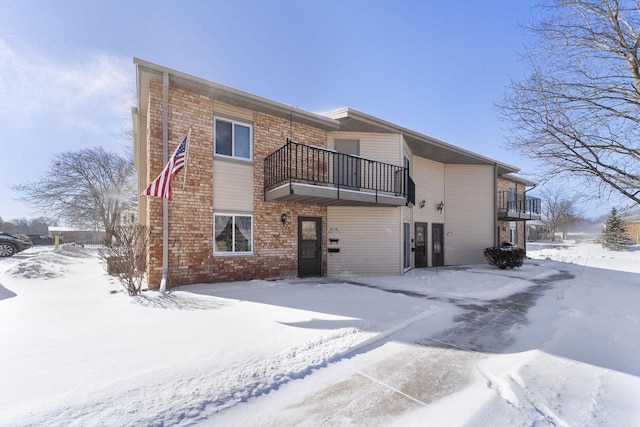 snow covered back of property featuring a balcony