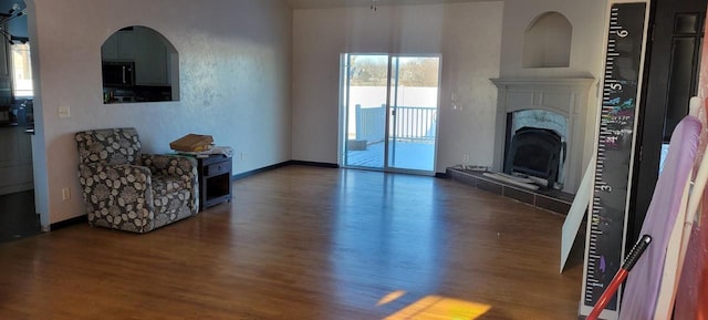 living room featuring dark wood-type flooring and a tiled fireplace